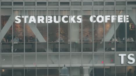 Gente-En-La-Cafetería-Starbucks-En-El-Cruce-De-Shibuya-En-Un-Día-Lluvioso-En-Tokio,-Japón