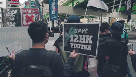 Demonstranten-Mit-Save-12-Hk-Jugendplakat-In-Tokio,-Japan---Solidarität-Mit-Hongkong-Protest---Mittlere-Aufnahme,-Rückansicht