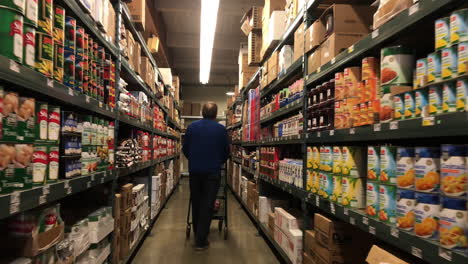 Male-Shopper-Wearing-Mask-And-Walking-In-The-Aisle-At-Smart-Foodservice-Warehouse-Store-With-A-Pushcart