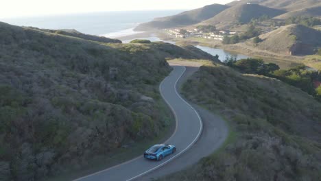 Fahrendes-Bmw-I8-Sportcoupé-In-Der-Landschaftlich-Reizvollen-Straße-Der-Marinlandzungen-Bei-Sonnenuntergang-Aus-Der-Luft