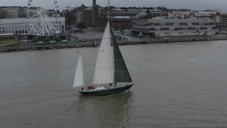 Drone-footage-of-sailing-boat-near-the-city-coast-and-Ferris-wheel