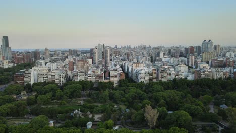 Palermo-Japanese-gardens-woodland-park-under-Buenos-Aires-urban-cityscape-skyline-aerial-push-in