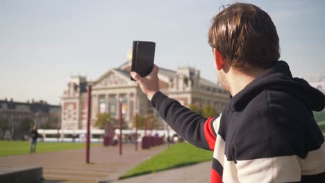 Handsome-young-man-recording-video-near-the-Concertgebouw-in-Amsterdam-with-the-cellphone