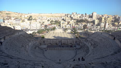 Ein-Standbild-Des-Römischen-Theaters-In-Amman-Mit-Klarem-Blauem-Himmel-Und-Häusern-Im-Hintergrund