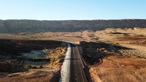 Cinematic-Vertical-Pan-of-Black-Tarmac-Road-Cutting-Through-the-Desert