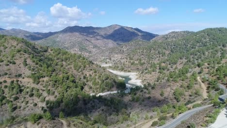 Tiro-Aéreo-De-Drones-Volando-Hacia-Las-Montañas-Sobre-La-Represa-De-Farmakas-En-Chipre