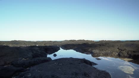 Crystal-clear-tide-pool-encapsulated-by-a-lava-rock-formation