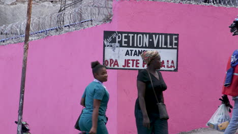 Letrero-De-Petion-ville-Con-Personas-Y-Autos-Pasando-Frente-Al-Letrero