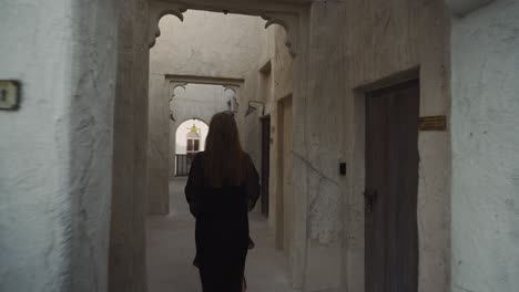 Mujer-Vestida-De-Negro-Está-Caminando-Por-Un-Edificio-Antiguo-En-Los-Emiratos-De-Dubai