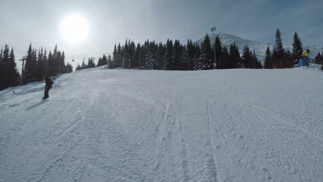 Snowboarder-doing-trick-flips-downhill-on-ski-resort-slopes