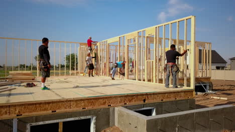 A-drone-shot-slowly-floating-around-construction-framers-putting-up-walls-on-a-new-home-in-the-process-of-being-built