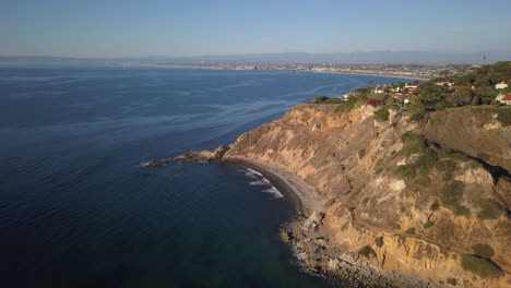aerial-shot,-going-forward-along-a-cliff-in-Palos-Verdes,-near-Los-Angeles,-California,-with-Hermosa-beach-and-Manhattan-beach-in-the-background