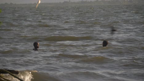 Toma-En-Cámara-Lenta-De-Jóvenes-Africanos-Jugando-En-Las-Olas-Y-El-Oleaje-Del-Lago-Victoria-En-áfrica