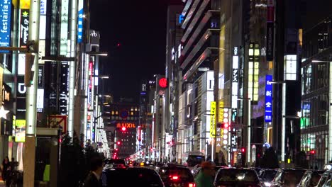 La-Vista-De-La-Famosa-Calle-Comercial-Ginza,-Autos-Y-Gente-Caminando-Por-La-Noche