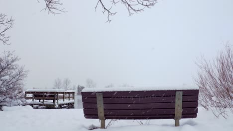 Schnee-Fällt-Vor-Dem-Hintergrund-Einer-Parkbank