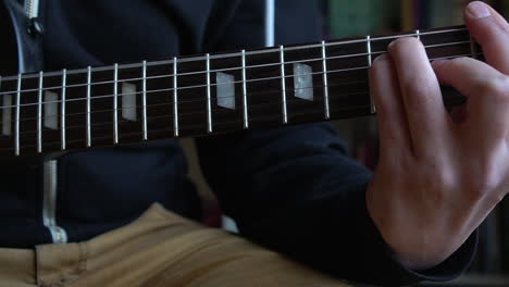 Hombre-Practicando-Una-Guitarra-Eléctrica-Negra-Vintage,-Ensayando-Acordes,-Solos-Y-Octavas-En-Un-Ambiente-De-Luz-Natural.