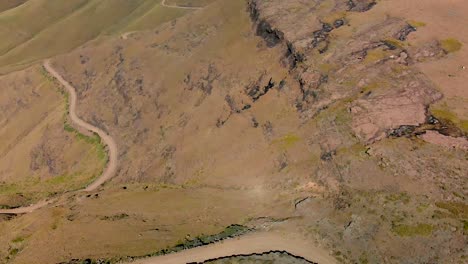 Aerial-view-of-a-green-valley-with-switchback-gravel-roads-60-fps