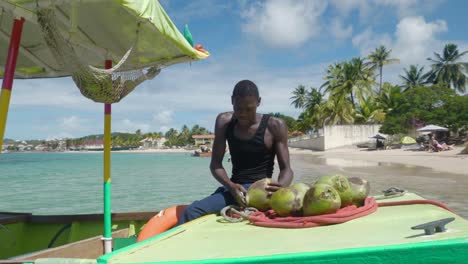 Bartender-chops-fresh-coconuts-for-tropical-drinks-on-floating-bar-anchored-at-beach