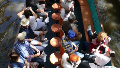 Boat-full-of-tourists-coming-from-under-bridge-and-going-down-canal-on-Riverwalk