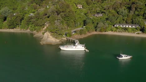 SLOWMO---Boats-docked-in-bay-by-beach-during-summer-in-Marlborough-Sounds,-New-Zealand