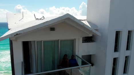 Toma-Aérea-De-Una-Pareja-En-Una-Suite-Penthouse-En-La-Zona-Hotelera-De-Cancún-Con-El-Horizonte-Y-La-Playa-Al-Fondo