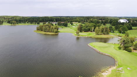 Vista-Aérea-De-Pájaro-Del-Campo-De-Golf-En-Estocolmo-Junto-Al-Lago