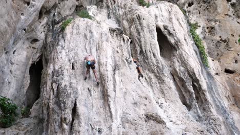 Young-travelers-with-a-rope-engaged-in-the-sports-of-rock-climbing-on-the-rock-at-Krabi-in-Thailand