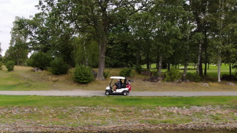 Jugadores-De-Golf-Conduciendo-Hacia-El-Siguiente-Tee,-Tiro-De-Seguimiento-Aéreo