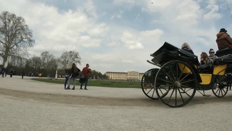 Horse-carriage-with-tourists-passing-in-the-back-gardens-of-Schönbrunn-Palace,-Vienna