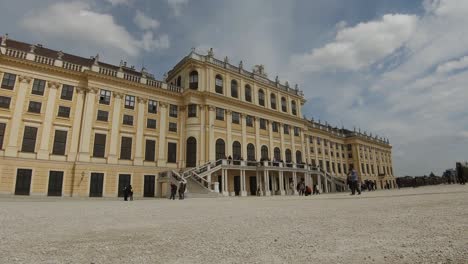 The-back-of-Schönbrunn-Palace,-Vienna,-with-tourists-on-a-partly-cloudy-afternoon