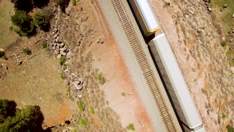 Aerial-overhead-footage-railroad-cars-pass-slowly-below-a-drone