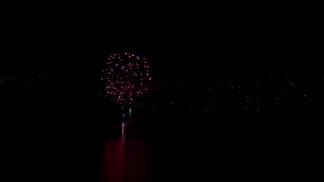 Aerial-drone-shot-of-Fireworks-display-over-a-large-lake-in-rural-Australia