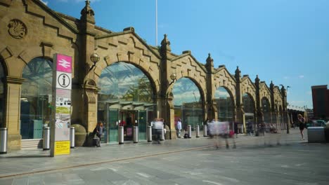 Zeitraffer-Des-Bahnhofseingangs-Von-Sheffield-Mit-Menschen,-Die-In-Den-Bahnhof-Ein--Und-Ausgehen,-Und-Wolken,-Die-An-Einem-Sonnigen-Tag-Vorbeiziehen,-4k-25p