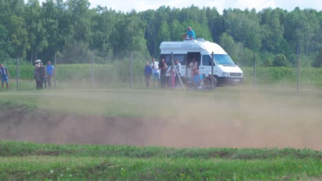 Los-Autos-De-Autocross-Compiten-En-Carreras-De-Aficionados-En-La-Pista-De-Tierra-En-Un-Día-Soleado-De-Verano,-La-Gente-Mira-Los-Autos-Que-Pasan,-Tiro-Medio-Desde-La-Distancia