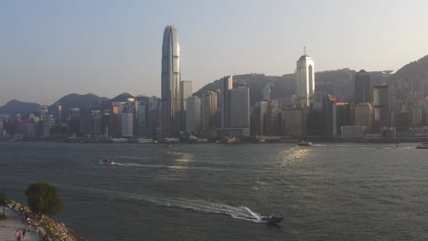 Fly-over-Victoria-harbor-in-Hong-Kong-during-a-sunny-day-with-boat-passing-by