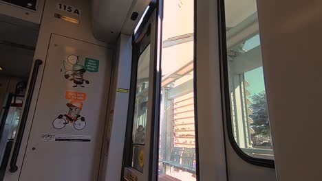 Speed-ramp-At-one-of-Phoenix-Metro-Light-Rail-Stations,-a-lone-man-in-a-hoodie-walks-past-the-open-train-door-which-close-and-the-train-takes-off