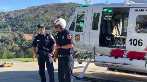 Dos-Pilotos-De-Helitack-Hablando-Con-Los-Niños-Sobre-La-Seguridad-Contra-Incendios-Mientras-Uno-Se-Pone-Un-Casco-Con-Gafas-Especiales-Para-Evitar-La-Entrada-De-Escombros