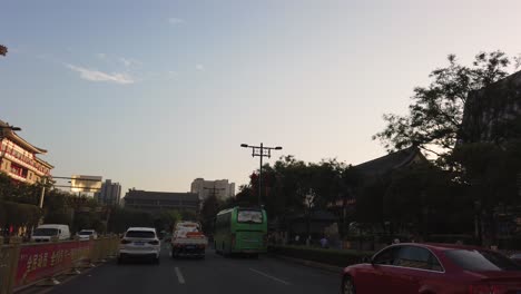 Xian,-China---July-2019-:-Car-front-view-of-the-green-bus-and-traffic-on-busy-street-in-the-city-of-Xian-in-summer,-Shaanxi-Province,-central-China