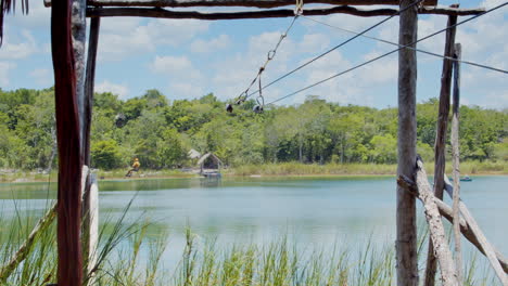 Wide-shot-of-man-zip-lining-over-the-pond-in-Chunyaxche,-Quintana-Roo,-Mexico