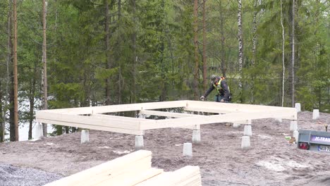 Static-shot-of-a-worker-measuring-plank,-building-the-foundation-to-a-house,-in-Ostrobothnia,-Finland