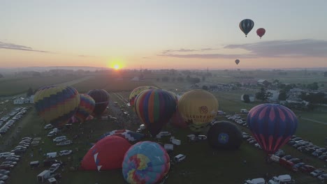 Vista-Aérea-De-Un-Amanecer-Globos-Aerostáticos-Despegando-En-Un-Festival-De-Globos-En-Una-Clara-Mañana-De-Verano