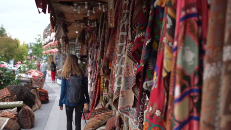 Mujer-Turista-Caminando-Por-Un-Popular-Barco-De-Alfombras-Turcas-En-Goreme,-Turquía-Con-Auténticas-Alfombras-Turcas-Colgando