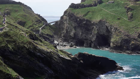 Leute-Im-Urlaub,-Die-Auf-Einer-Klippe-Entlang-Des-Pfades-Spazieren,-Der-Zu-Den-Ruinen-Von-Tintagel-Castle-Und-Zur-Brücke-Zur-Insel-In-Cornwall-Führt