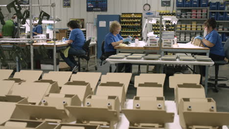 Sliding-shot-of-a-team-of-quality-control-specialists-working-in-a-manufacturing-facility-with-finished-product-in-the-foreground