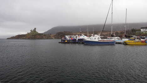 Static-shot-from-Kyleakin-town-with-dramatic-light-and-clouds-and-boats-on-Atlantic-ocean-in-the-port-at-Isle-of-Skye,-Scotland