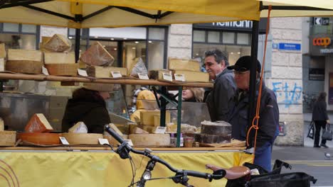 Medium-shot,-man-sampling-some-cheese-on-a-cheese-shop,-In-Basel-Switzerland