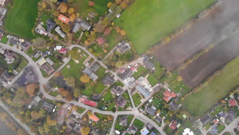 Small-rural-village-or-town-in-Germany-from-above,-ascending-aerial-time-lapse