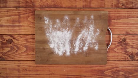 Sprinkling-wheat-flour-on-wooden-board-and-kneading-the-dough