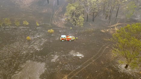 Feuerwehrleute-Löschen-Glut-Auf-Brennendem-Boden-Mit-Feuerwehrauto-Aus-Einem-Eukalyptus-Waldbrand,-Luftdrohnenüberführung-Enthüllt-Schuss