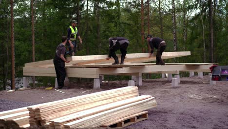 Team-of-Construction-Workers-Lift-Framed-Wall-Into-Place,-house-construction-site